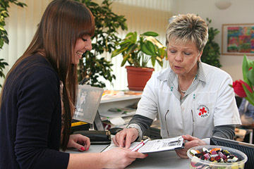 Foto: Frau wird von einer DRK-Mitarbeiterin bei der Blutspende empfangen.